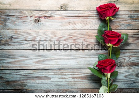 Bouquet of red roses on wooden rustic background.