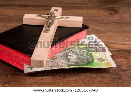 A crucifix lying on boards on a background of a book with Polish banknotes