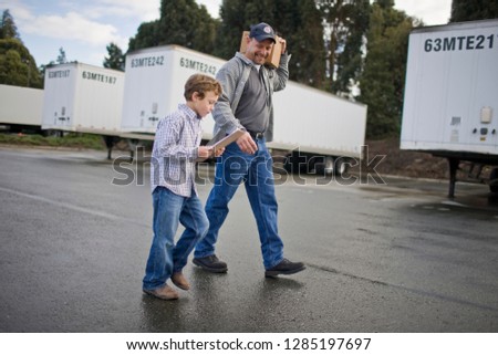 Young boy walking with his father through an outdoor freight yard.
