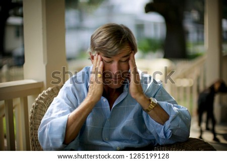 Mature man rubbing his temples with his eyes closed.