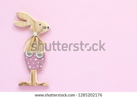Easter bunny. Wooden figurine rabbit on pastel pink paper background Concept Valentine's card or Happy Easter card Top view Minimal style Copy space Template for lettering, text or your design.