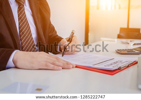 Young businessmen are sitting down to sign a joint investment contract on the table so that the contract is a link between business people and organizations that will do business together