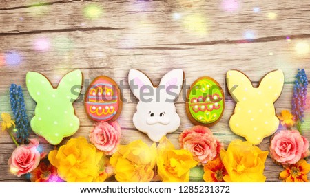 Easter composition with spring flowers and easter cookies on wooden background. Easter concept with copy space. Flat lay, top view.