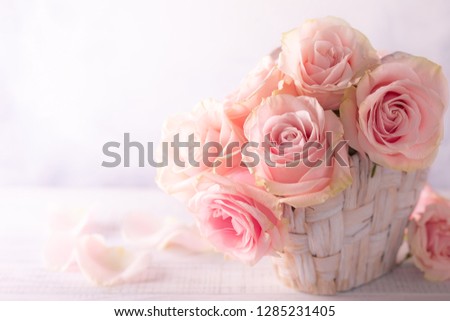 Beautiful pink roses in basket on vintage wooden table. Shabby chic style. Flower composition for holiday with copy space.