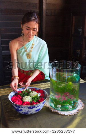 Young Beautiful Thai Asian woman dressing in vintage retro Traditional Thai costume arranging flower bowl. Thailand Cultural and Traditional Tourism, Asian Rural Daily Life, Thai Heritage concept.