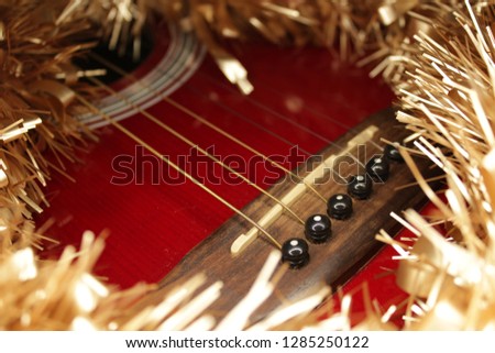Red acustic guitar, strings and tinsel