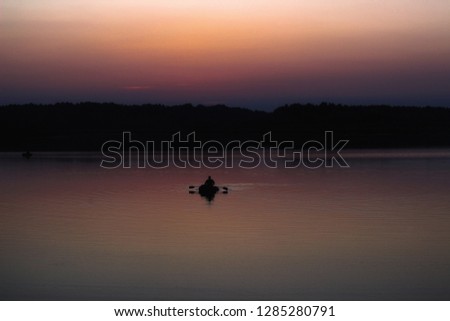 Silhouette of a man which floating on a boat on the sea at sunset time