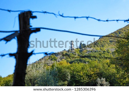 ancient monastery on the mountainside, through a barbed wire fence