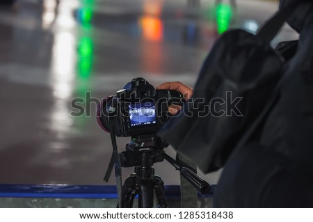 a photographer with a professional big camera photographs a skating rink at night