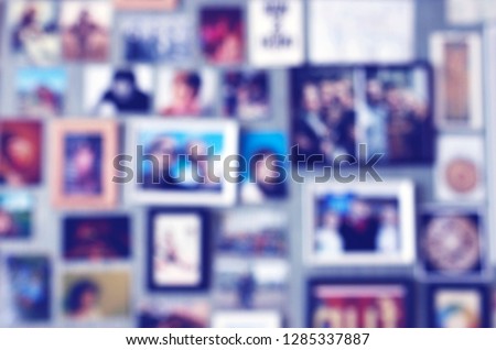 Blurred background with postcards and photos in frames put up on a wall. Collage of pictures with loved ones, friends or family. Concept for keeping good memories about holidays or vacation.