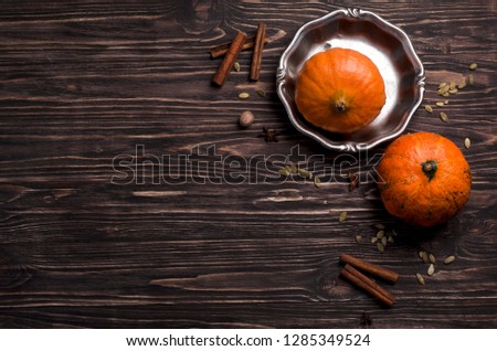 Pumpkins, pumpkin seeds, cinnamon sticks and spices on a dark wooden background. Top view, cooking process Royalty-Free Stock Photo #1285349524
