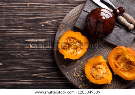 Top view of sliced pumpkin and pumpkin seeds, clay pot and cutlery on a wooden tray. Rustic style, autumn cooking concept Royalty-Free Stock Photo #1285349539