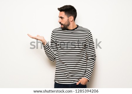 handsome man with striped shirt holding copyspace imaginary on the palm to insert an ad
