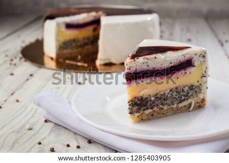 White chocolate sponge cake with fruit jelly and poppy on wooden background
