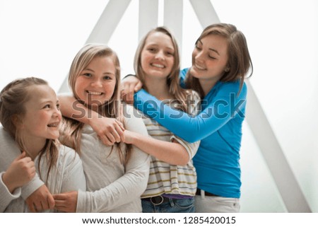 Portrait of four smiling sisters standing side by side with their arms around each other.