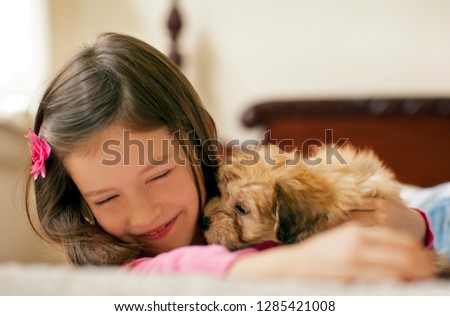 Young girl lying on a bed with a puppy.