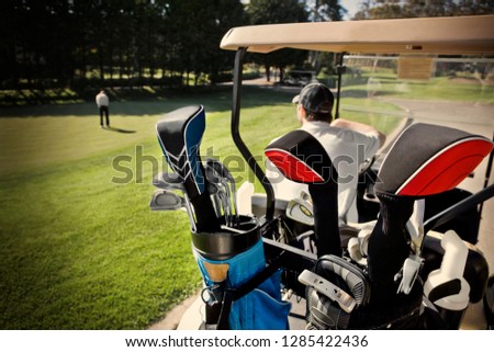 Golf clubs inside a golf bag in the back of a golf cart at a golf course.