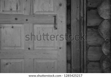 A fragment of a log wall and a wooden door with a metal hook. Figures and lines.
