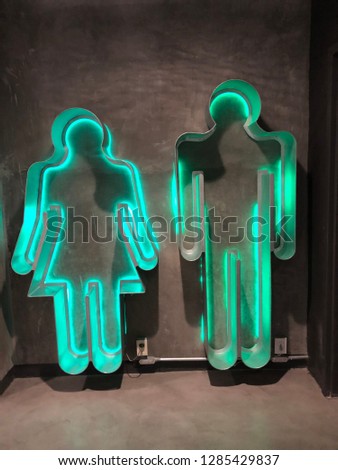 An old neon men and woman restroom sign.