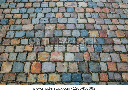 Colorful cobblestone surface made of red, yellow, orange, grey, blue, purple and white rectangular pieces of stone, top view, european city