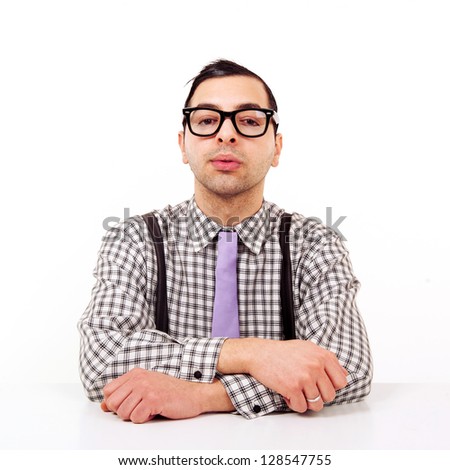 Funny portrait of young nerd with eyeglasses at the desk isolated on white background.