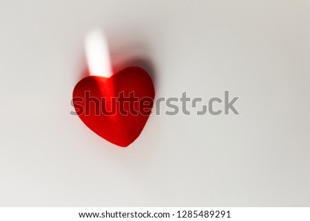 Decorative red heart on a white background with sun rays and shadow. Space for your text 