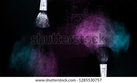 Cosmetic brush with purple and blue ocean cosmetic powder spreading for makeup artist or graphic design in black background