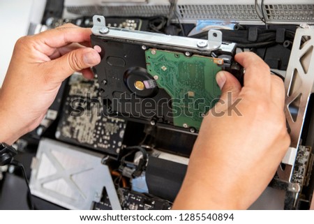We can see the hands of the engineer when he places a new hard drive on a desktop computer
