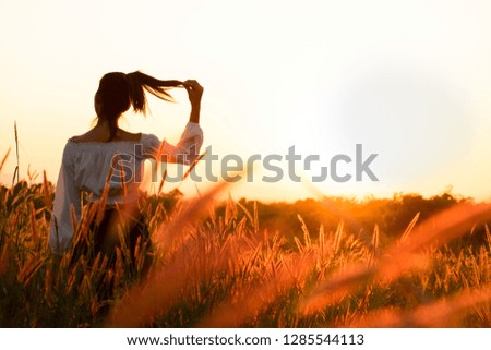 Beautiful young asian woman in a field at sunset