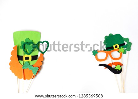 Festive masks for a St. Patrick's Day on a white background. Fancy dress. Party Concept. Flat lay objects with paper craft on white wallpaper at home office desk with copy space.