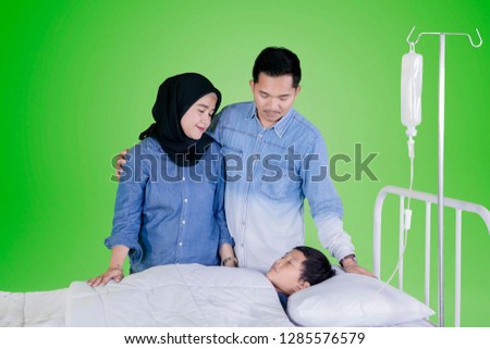 Picture of young parents standing in the studio while accompanying their sick son