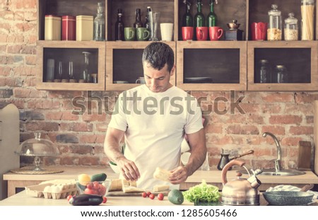 young attractive man doing sandwiches in the kitchen