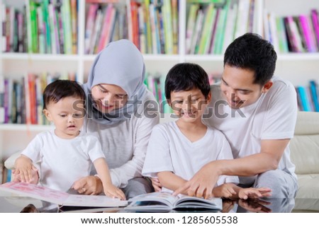 Picture of Asian family sitting on the couch while reading books together in the library