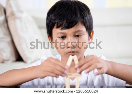 Picture of Asian little boy building a house of wooden blocks. Dream house concept.