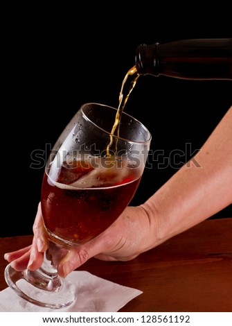 pouring an irish red ale beer into a chalice on a black background
