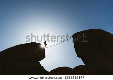 a man balancing walking on rope over precipice. Business, risk taking, challenge,bravery, and concentration Royalty-Free Stock Photo #1285612147