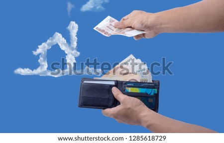 Open wallet with cash money and credit cards in man hands on sky with clouds is home background. Payment concept. Dream Home. Buying a house.
