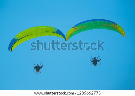 Picture of the Paramotors Flying through  blue sky background.