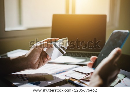 Business man hand hold credit card to buying online product in his mobile application in his office workplace.