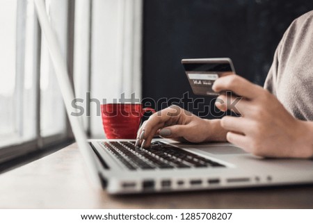 Woman hand holding credit card and using laptop. Online shopping, spending money concept
