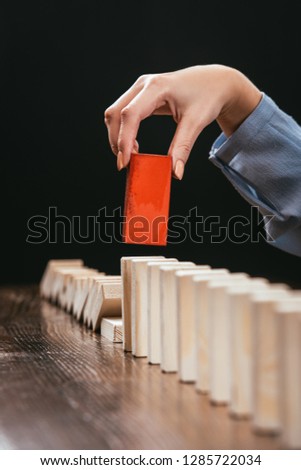 cropped view of woman picking red wooden brick from row of blocks isolated on black