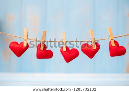 Red heart shape decoration hanging on line with copy space for text on blue wooden background. Love, Wedding, Romantic and Happy Valentine’ s day holiday concept