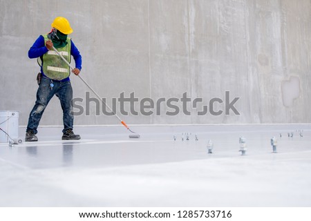 Construction worker coating floor by epoxy  Royalty-Free Stock Photo #1285733716