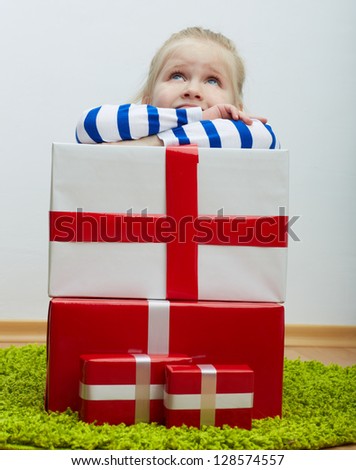 Little girl with white hair and many gifts . Seat on floor. Looking up .