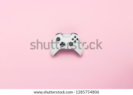 White gamepad on a pink background. Concept game on the console, computer games. Flat lay, top view.
