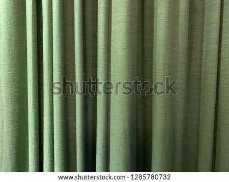 Green fabric background. Draped curtain hanging close-up. Empty Texture. Wide Screen Web Banner With Copy Space.