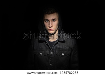 Portrait of a serious young man in the hood black background