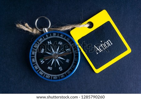 ACTION inscription written on tag and compass on black background with selective focus and crop fragment. Business and education concept