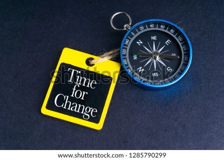 TIME FOR CHANGE inscription written on tag and compass on black background with selective focus and crop fragment. Business and education concept