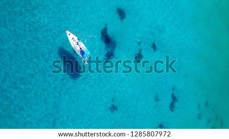 Aerial top view photo of yacht cruising in turquoise clear sea of Ionian island